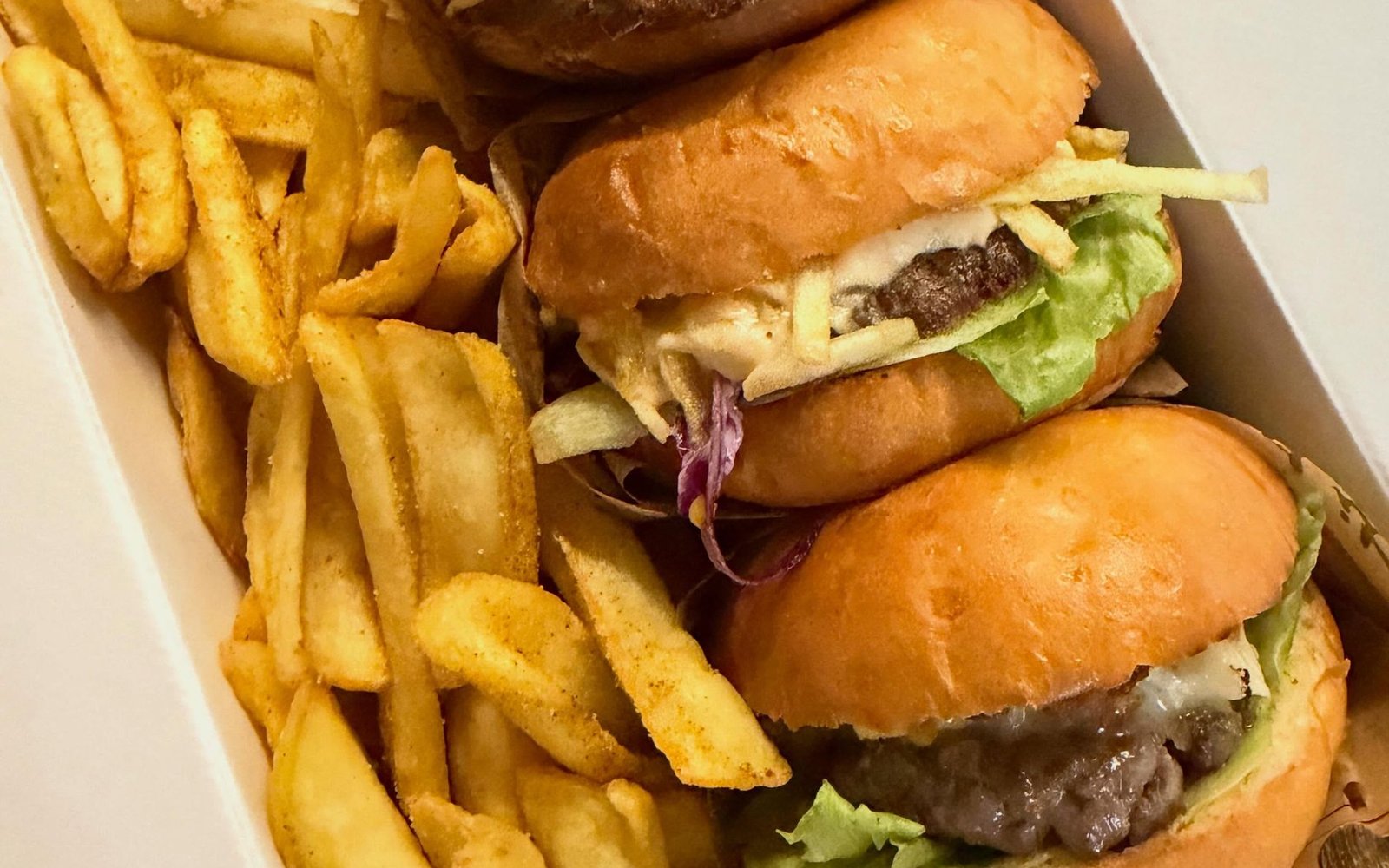 Cuatro hamburguesas de The Royal Burger en caja para llevar, con patatas fritas