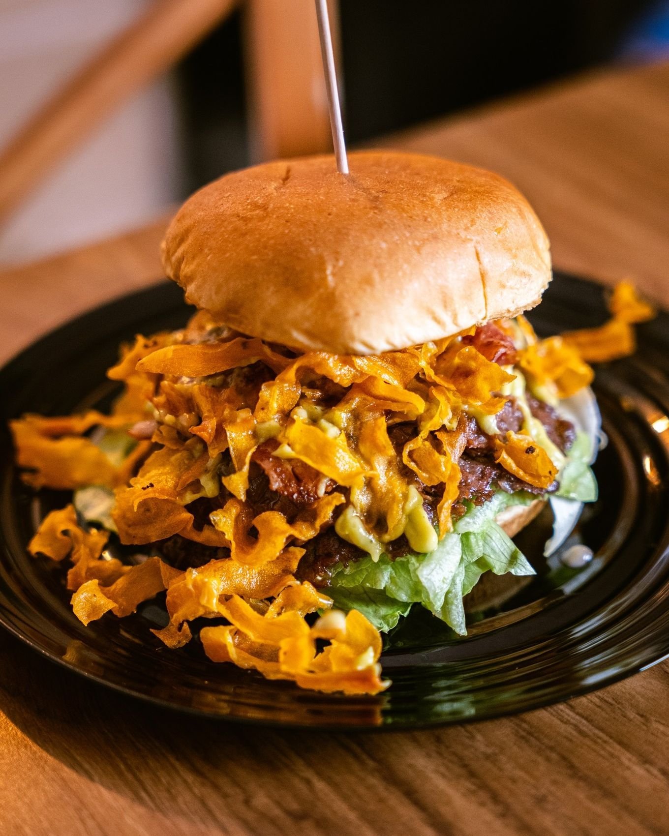 La Ciega, hamburguesa coronada con queso crujiente, en plato negro