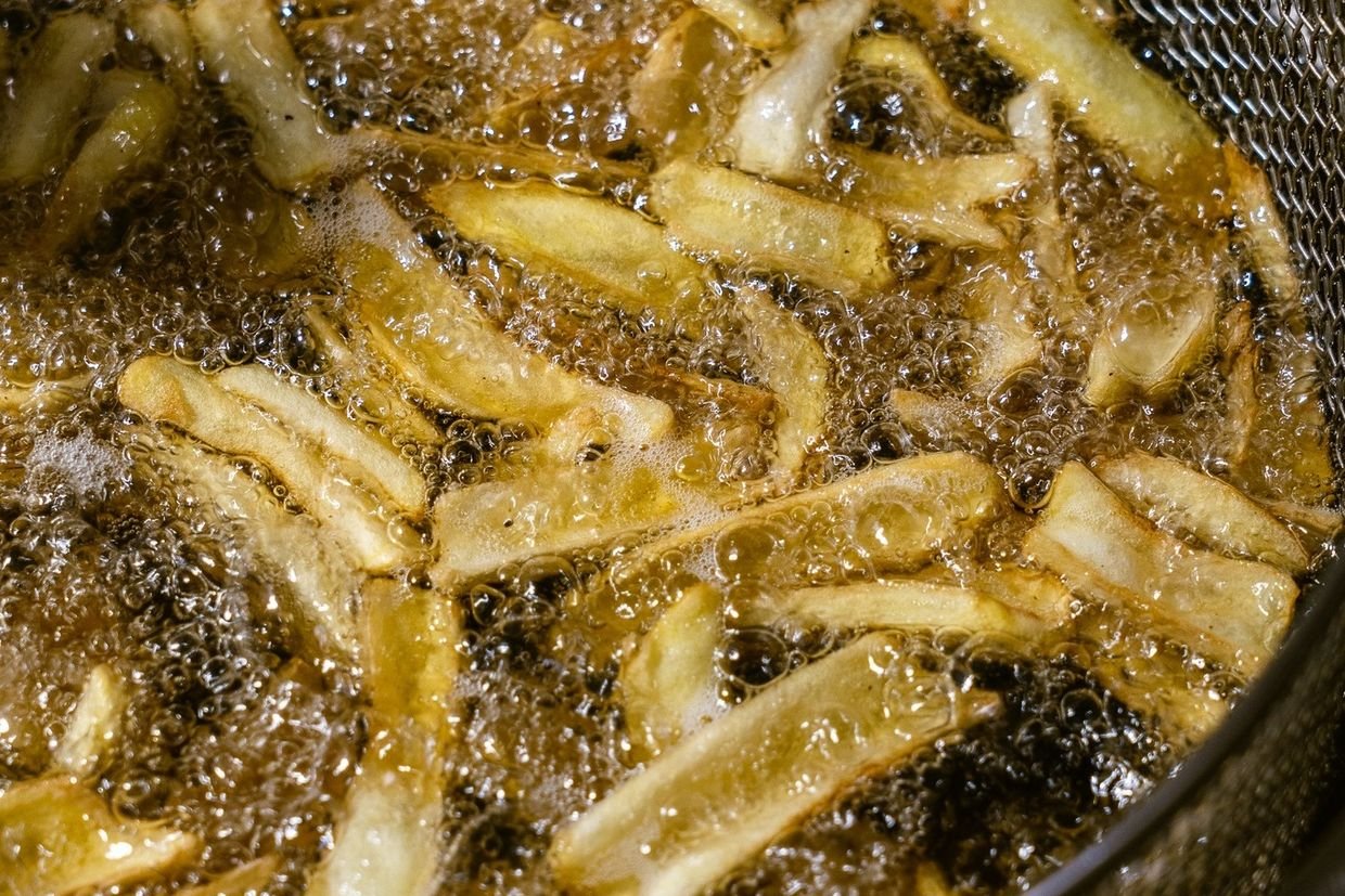 Patatas friendose en la cesta de la freidora